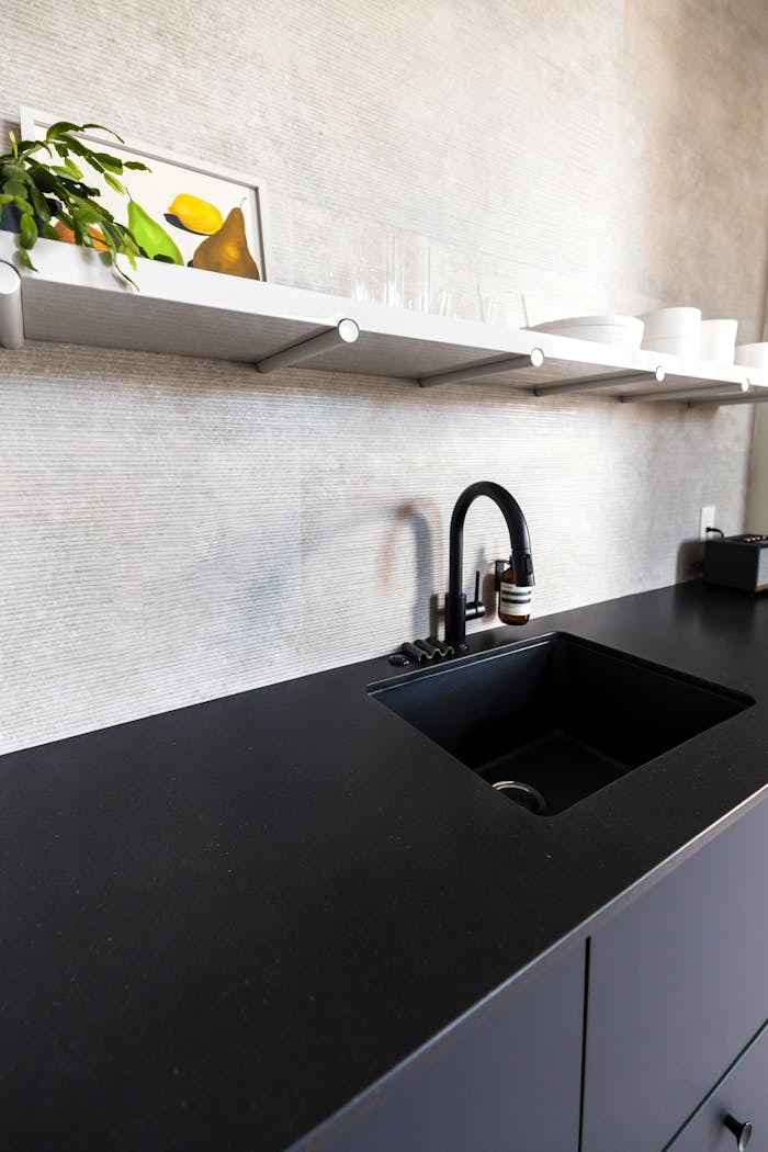 Bright minimalist kitchen interior featuring sleek black sink and stylish shelving.